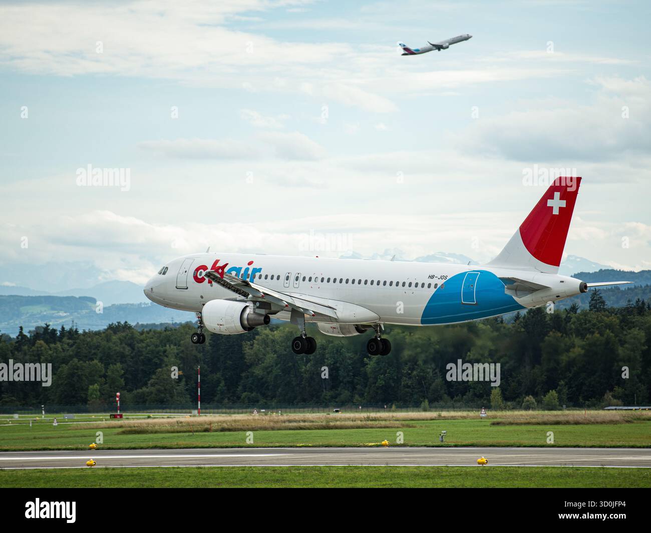 Atterraggio alla pista dell'aeroporto - Jet commerciale con bandiera svizzera in volo Foto Stock
