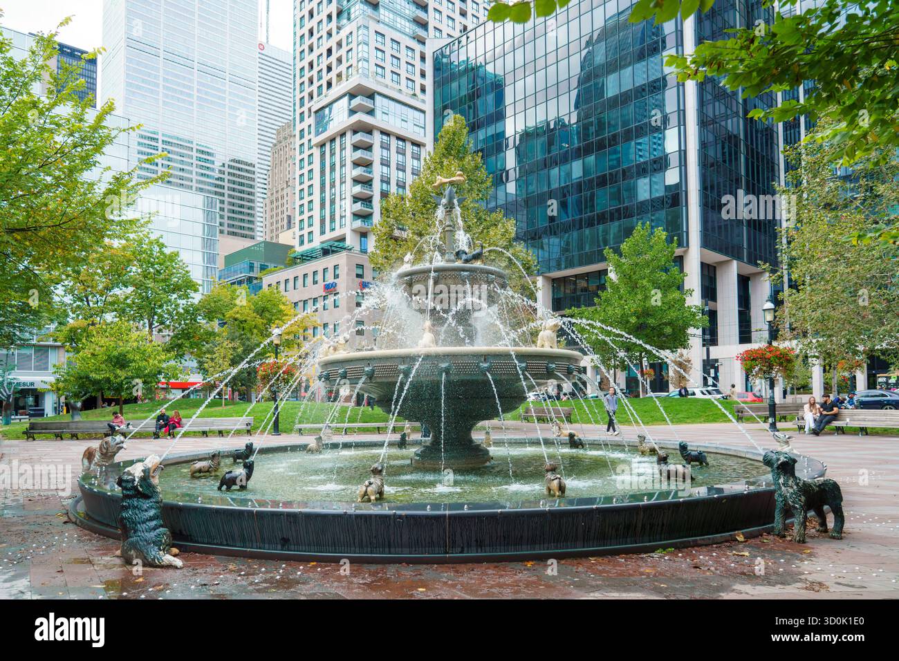 Berczy Park Fountain, con sculture di cani che spruzzano acqua circondata da alberi e edifici del centro. Foto Stock