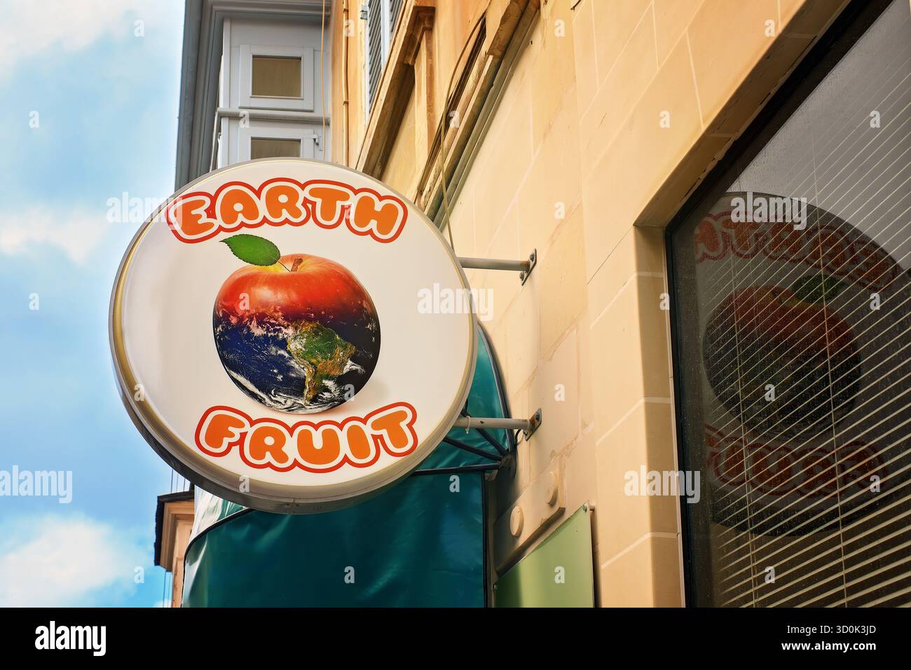 Sliema, Malta - 10.19.2025: Segno rotondo di frutta terrestre con un logo creativo di frutta a forma di pianeta su un muro di edificio sotto il cielo blu, che simboleggia mangiare sano Foto Stock