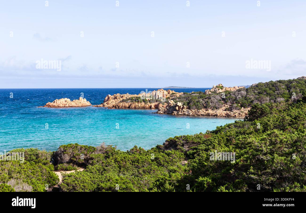 Vista panoramica di Cala Andreani sull'isola di Caprera, Italia. Il turchese Mar Mediterraneo e i lussureggianti cespugli di ginepro lungo la costa. Foto Stock