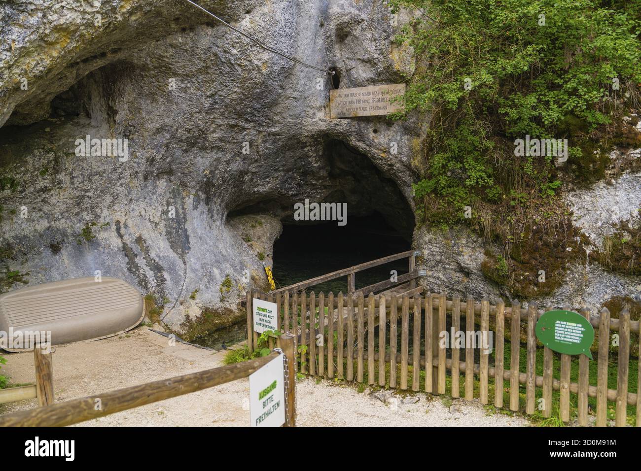 Recinzione in legno di fronte all'ingresso scuro di una grotta in un ambiente roccioso, Wimsener Hoehle, Hayingen, Germania Foto Stock