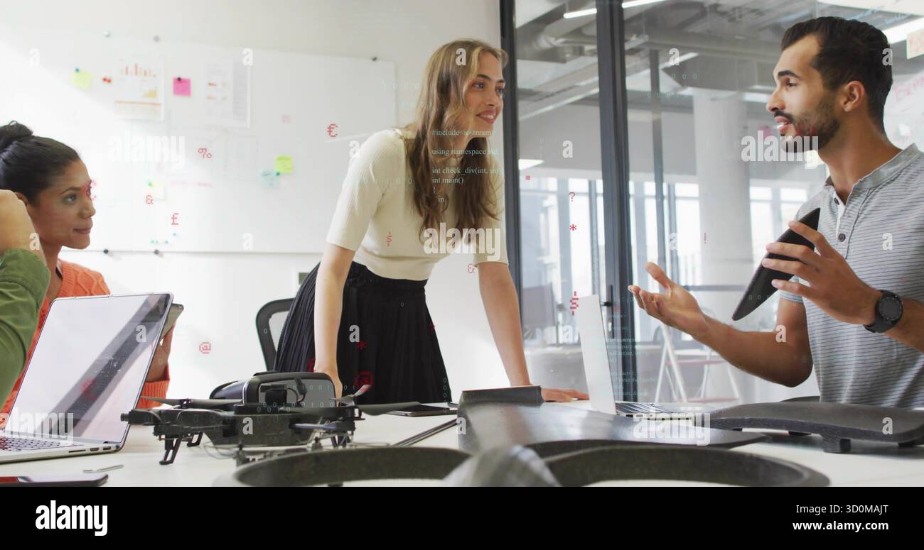 Donna pendente con i capelli castani che discute di piani con i colleghi intorno al tavolo dell'ufficio, con drone Foto Stock