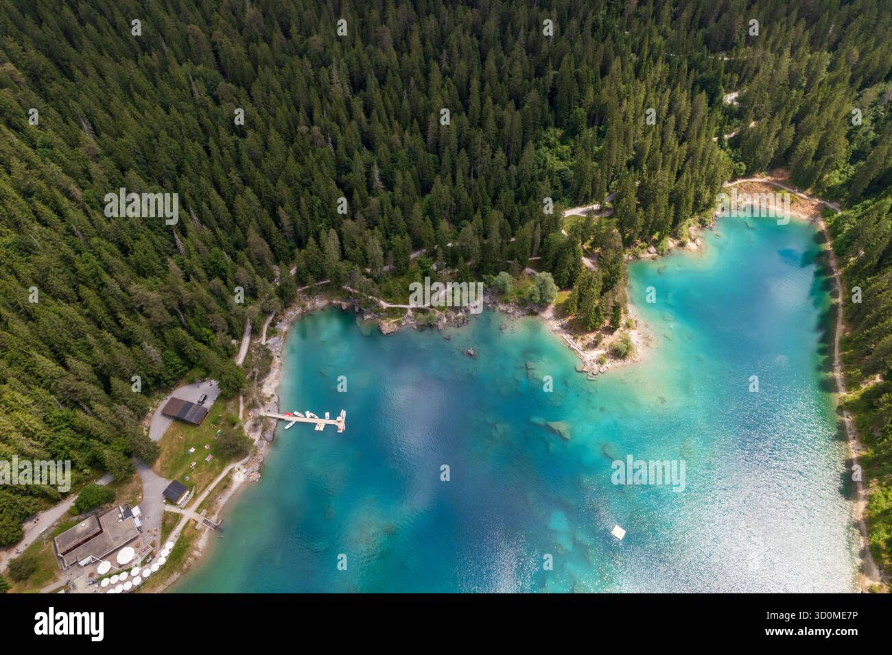 La vista aerea delle acque turchesi del lago incontra la fitta foresta verde, creando un incredibile contrasto tra la bellezza della natura: Caumasee, Grigioni, Svizzera. Foto Stock