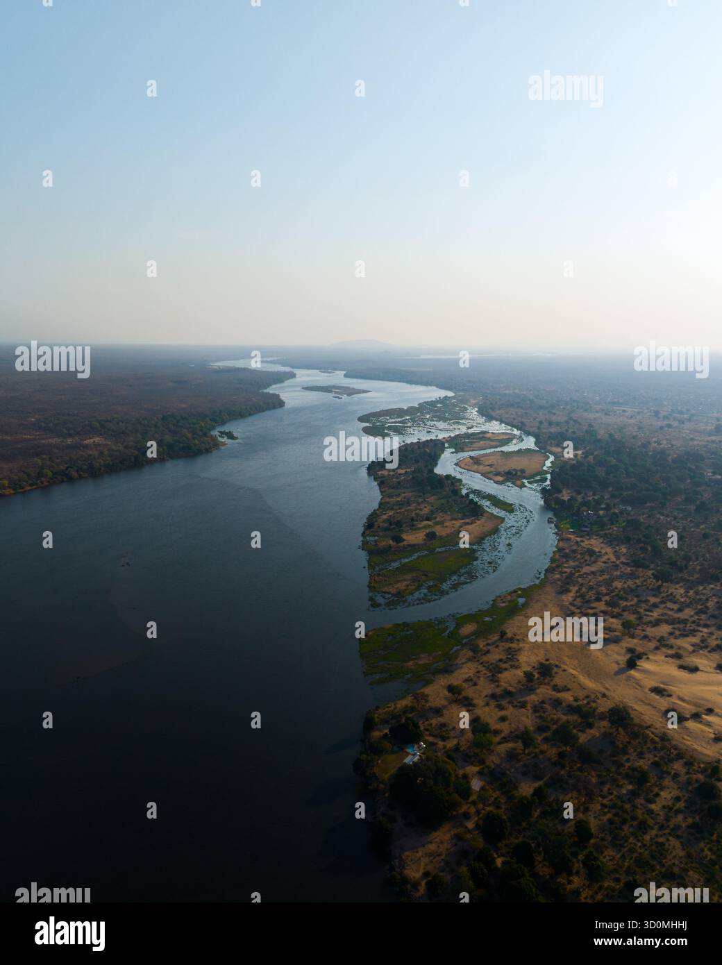 La vista aerea del fiume Zambesi attraversa il paesaggio aspro, con le sue acque che riflettono il vasto cielo sopra, il fiume Zambesi, la provincia centrale del Mashonaland, Zimbabwe. Foto Stock