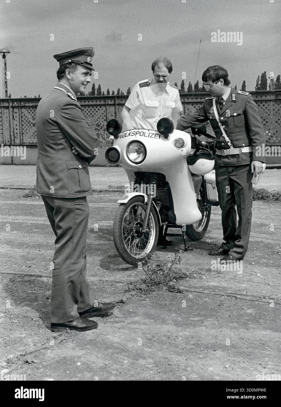 DEU, Germania, Berlino, 1990-03-18: I poliziotti di Berlino Ovest e Est si incontrano sul ponte Behmstrassenbruecke al confine tra il distretto occidentale di Wedding e il distretto orientale di Prenzlauer Berg. Una pattuglia motociclistica della polizia popolare mostra a un poliziotto di Berlino Ovest la sua moto, in primo piano un membro delle truppe di frontiera della RDT. [traduzione automatizzata] Foto Stock