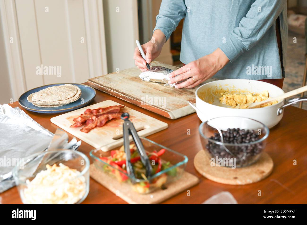 Donna in yoga top label preparazione pasti burrito per la colazione per congelatore Foto Stock