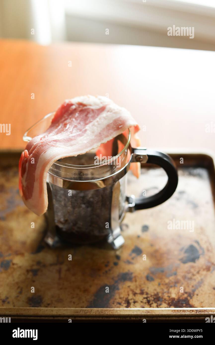 Fette di pancetta crude sulla macchina per il caffè French press Foto Stock