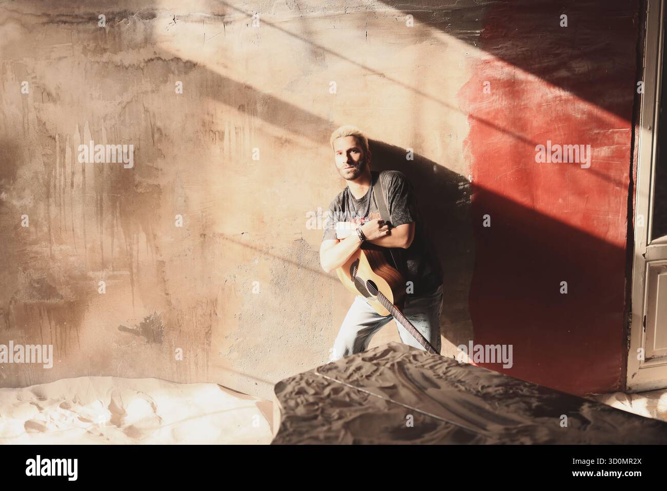 Il musicista suona la chitarra in uno spazio soleggiato abbandonato Foto Stock