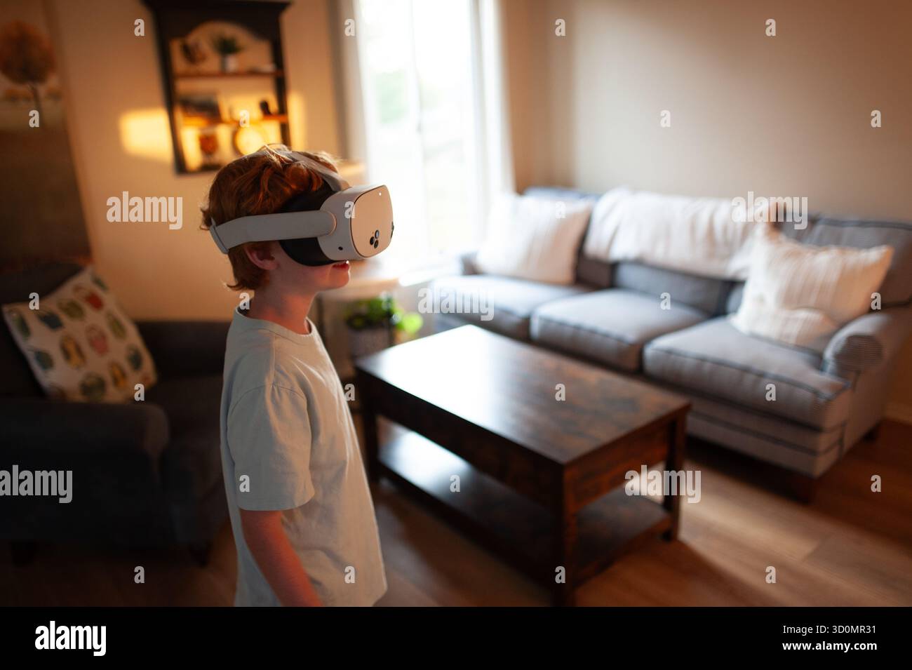 Bambino che indossa un visore VR e prova la realtà virtuale a casa Foto Stock