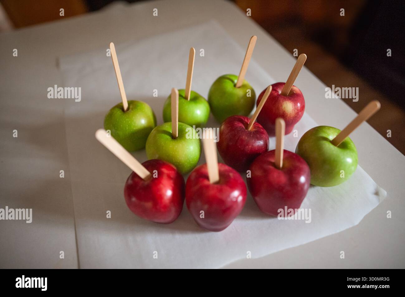 Mele verdi e rosse disposte ordinatamente su pergamena in una calda cucina Foto Stock