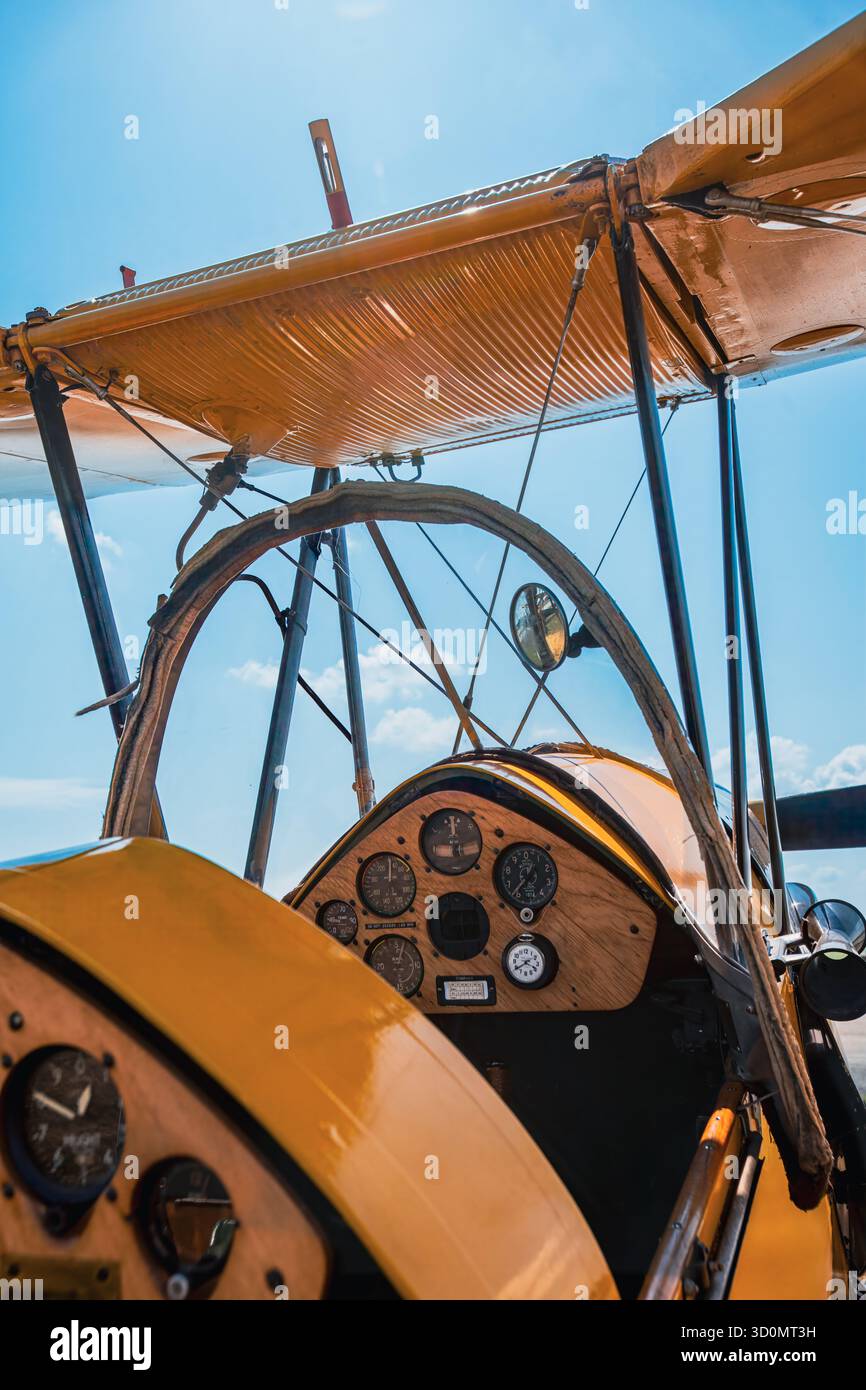 Vista interna dell'abitacolo di un biplano giallo d'epoca che mostra il quadro strumenti in legno con indicatori, dettagli di controllo e puntoni di supporto. L'angolo l Foto Stock
