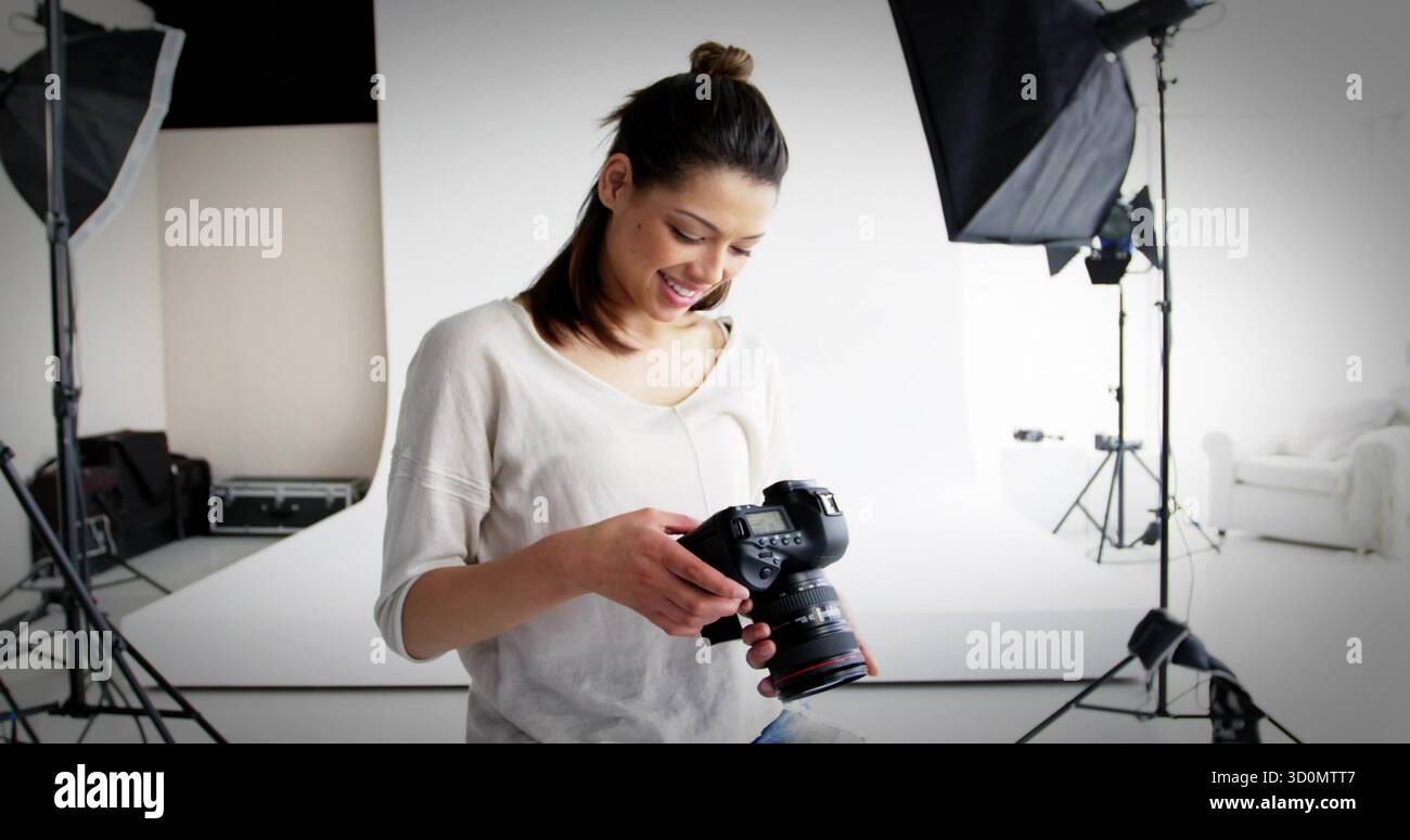 Con una fotocamera reflex digitale, donna che regola i comandi in uno studio fotografico, con supporti per la luce Foto Stock