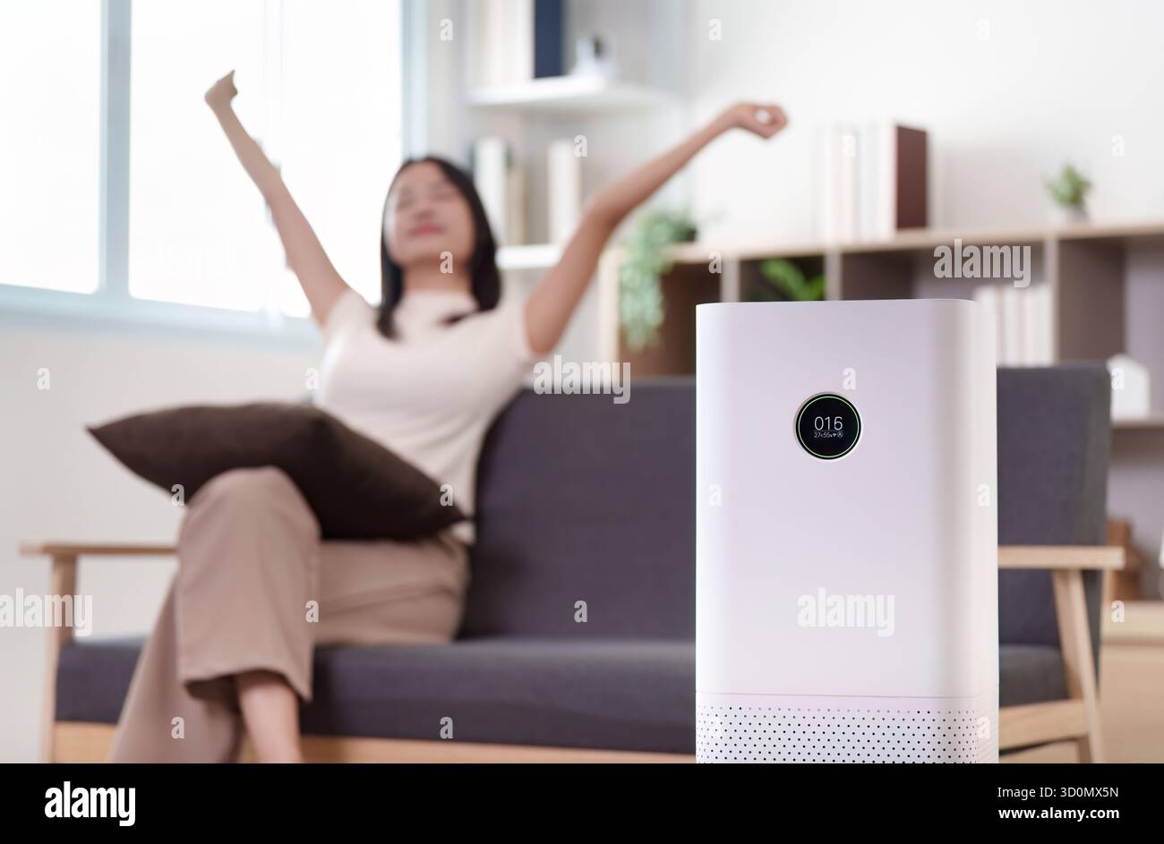 Casa intelligente. Donna che si rilassa con il purificatore d'aria nel soggiorno moderno. Foto Stock