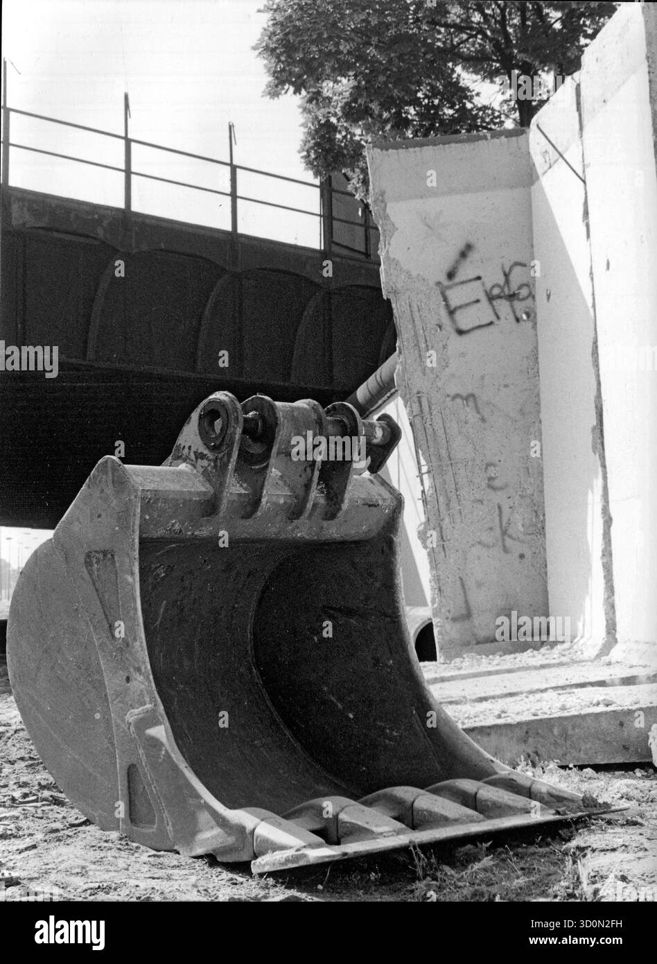 DEU, Germania, Berlino, 1990-03-18: Una pala da escavatore e segmenti di cemento strappati dal loro ancoraggio annunciano la caduta finale del muro di Berlino. Vista su Kiefholzstrasse al confine tra i distretti di Neukoelln (ovest) e Treptow (est). Sullo sfondo il ponte della Ringbahn ancora interrotta. HF [traduzione automatizzata] Foto Stock