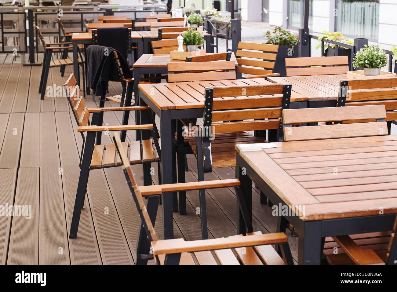 Terrazza vuota all'aperto con tavoli e sedie in legno. Moderna area salotto caffetteria. Non c'e' spazio per mangiare. Concetto di ospitalità urbana. Foto Stock