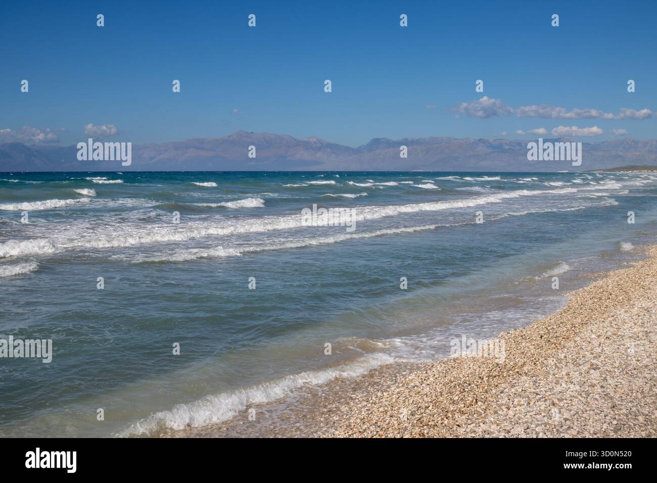 Mare Ionio con onde spettacolari durante una tarda giornata estiva. Montagne albanesi sullo sfondo. Cielo blu con nuvole bianche. A nord dell'isola di Corfù ( Foto Stock