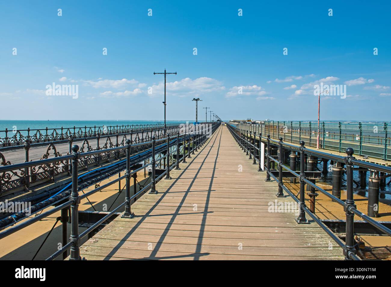 Lareg, antica e tradizionale località balneare, molo in legno che svanisce verso l'oceano marino in una prospettiva che diminuisce con ringhiere metalliche contro il blu Foto Stock