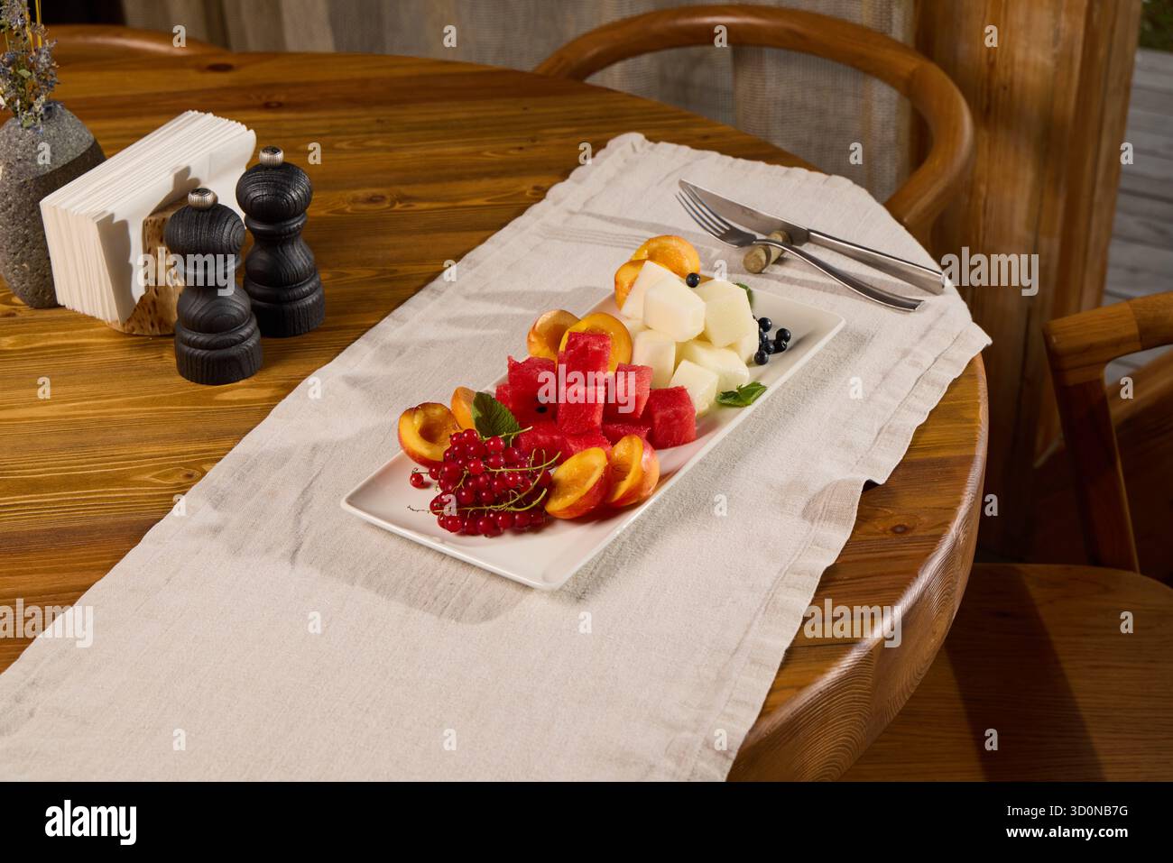 Un vivace e colorato vassoio di frutta fresca su uno splendido tavolo in legno che trasuda fascino Foto Stock
