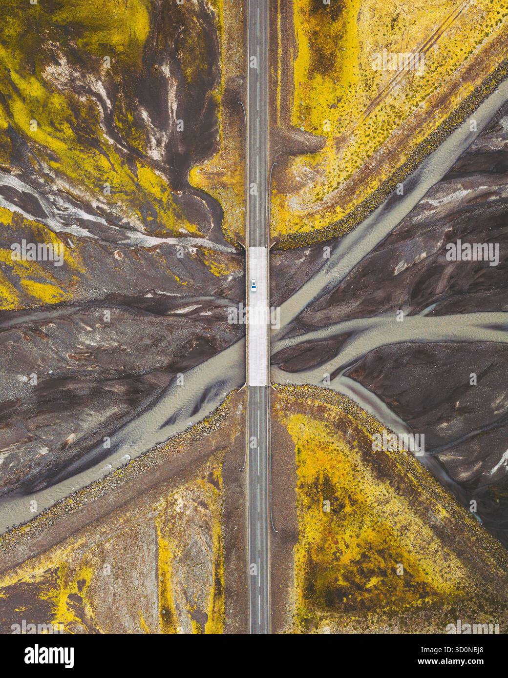 Veduta aerea di un ponte che taglia attraverso il netto contrasto tra campi ocra e fiumi ghiacciati grigi, Fjallsárlón, Sveitarfélagið Hornafjörður, Islanda. Foto Stock