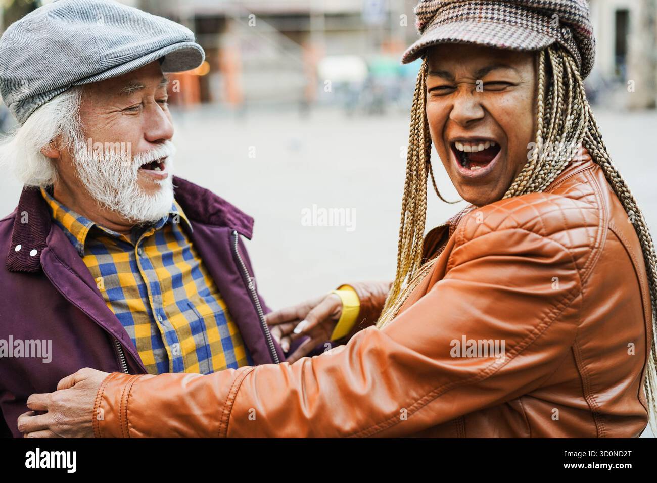 Coppia senior multirazziale che si diverte all'aperto con la città sullo sfondo - concetto di amore, relazione e gioioso stile di vita degli anziani Foto Stock