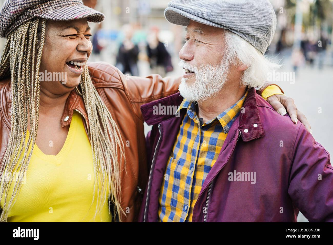 Coppia senior multirazziale che si diverte all'aperto con la città sullo sfondo - concetto di amore, relazione e gioioso stile di vita degli anziani Foto Stock