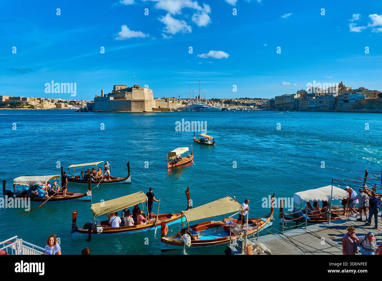 Luminose cabinovie maltesi e storico forte a la Valletta Malta con acqua blu e cielo soleggiato Foto Stock