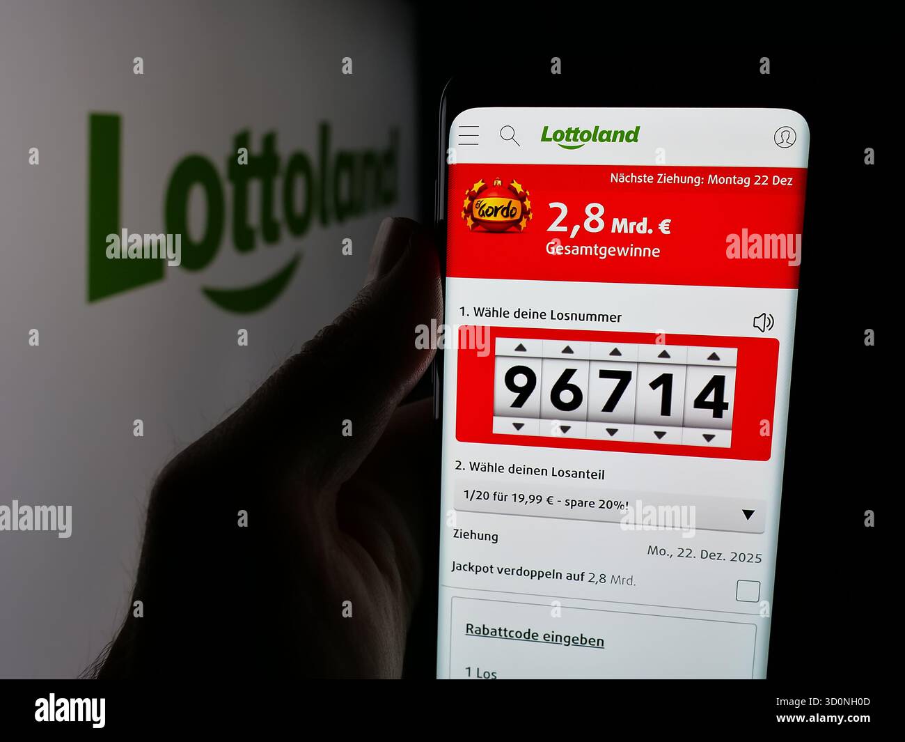 Stoccarda, Germania - 17-10-2025: Persona che detiene lo smartphone con pagina web della lotteria online Lottoland Limited sullo schermo davanti al logo. Concentrati Foto Stock