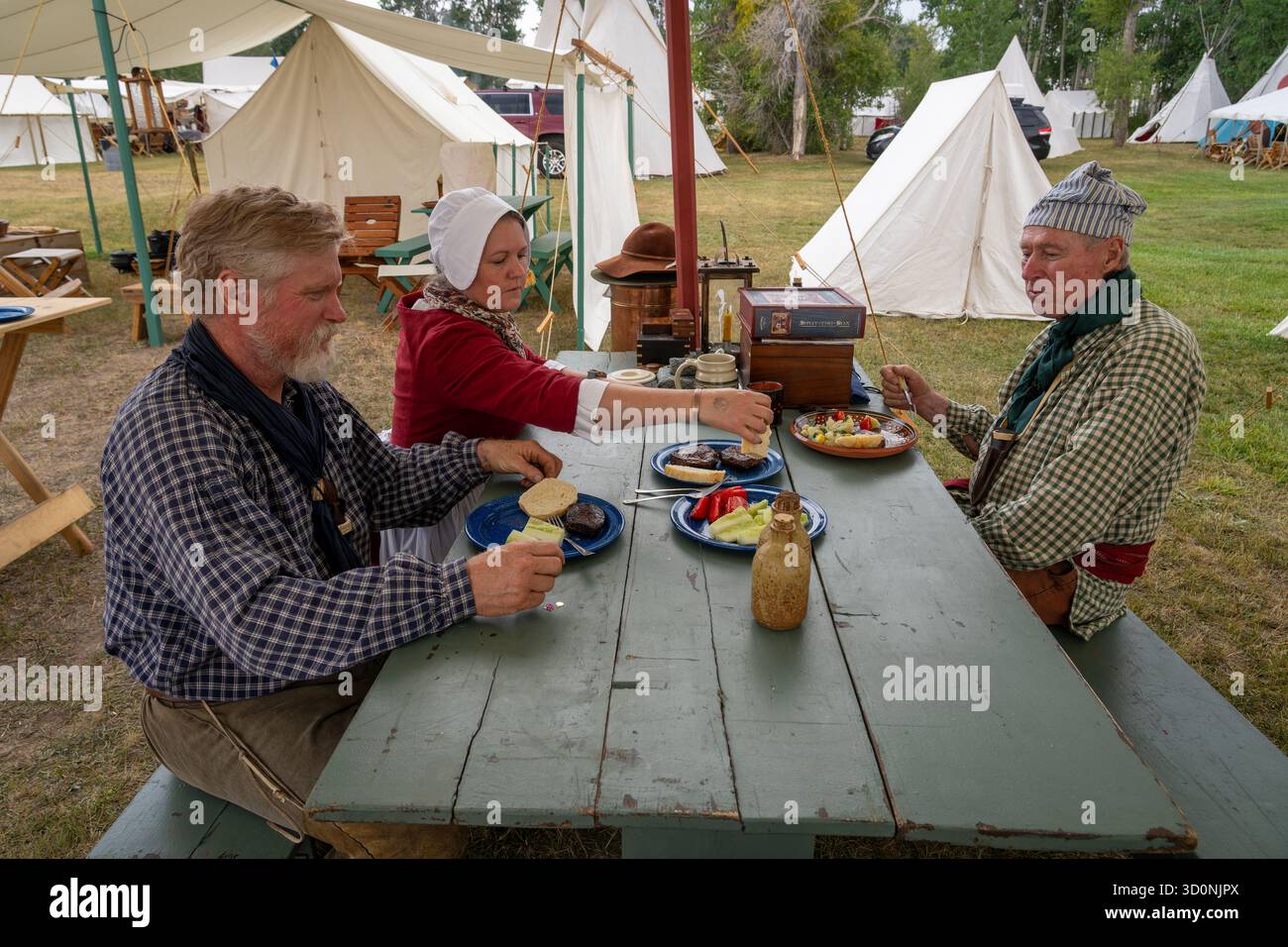 Le persone in abito d'epoca cenano nell'accampamento primitivo del Fort Bridger Rendezvous, sito storico di Fort Bridger, Wyoming. Foto Stock