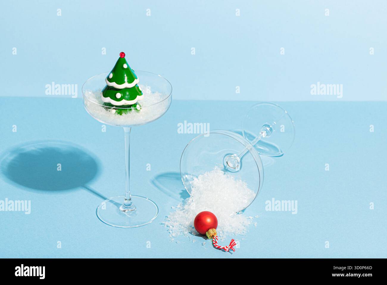 Albero di Natale e bauble rosso in bicchieri cocktail Martini su sfondo blu, spazio copia, estetica retrò. Concept design creativo per la festa di Natale. Foto Stock
