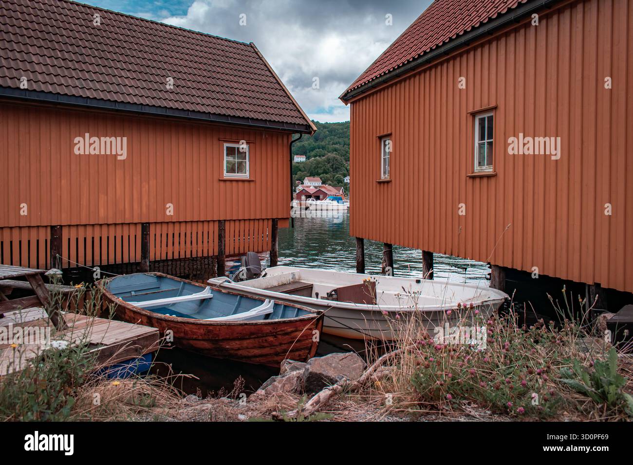 Una fila di barche colorate con barche attraccate all'interno, che si riflettono sull'acqua calma. Foto Stock