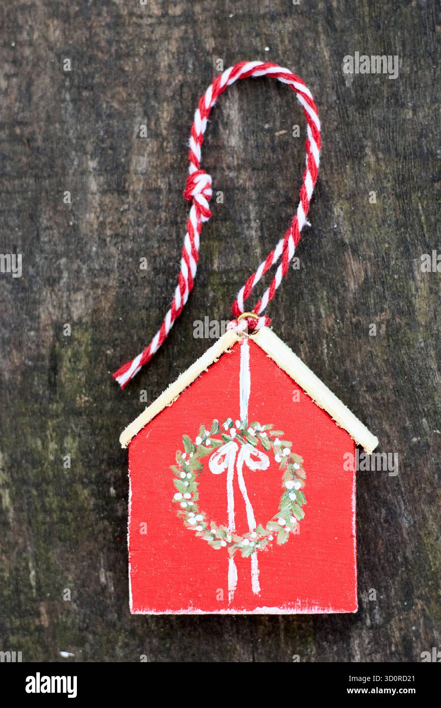 Incantevole decorazione per la casa in legno rosso con corona dipinta e spago Candy cane, un tocco di festa per l'arredamento natalizio e il fascino delle feste rustiche Foto Stock