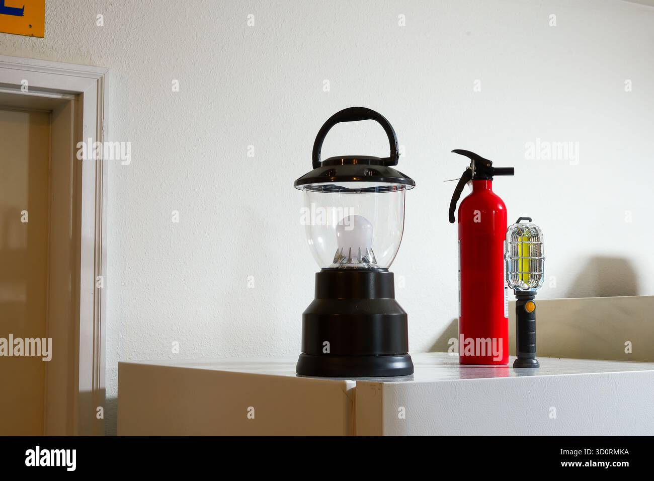 Una lanterna nera alimentata a batteria si trova sopra il frigorifero, vicino a un'altra luce e a un estintore. Foto Stock