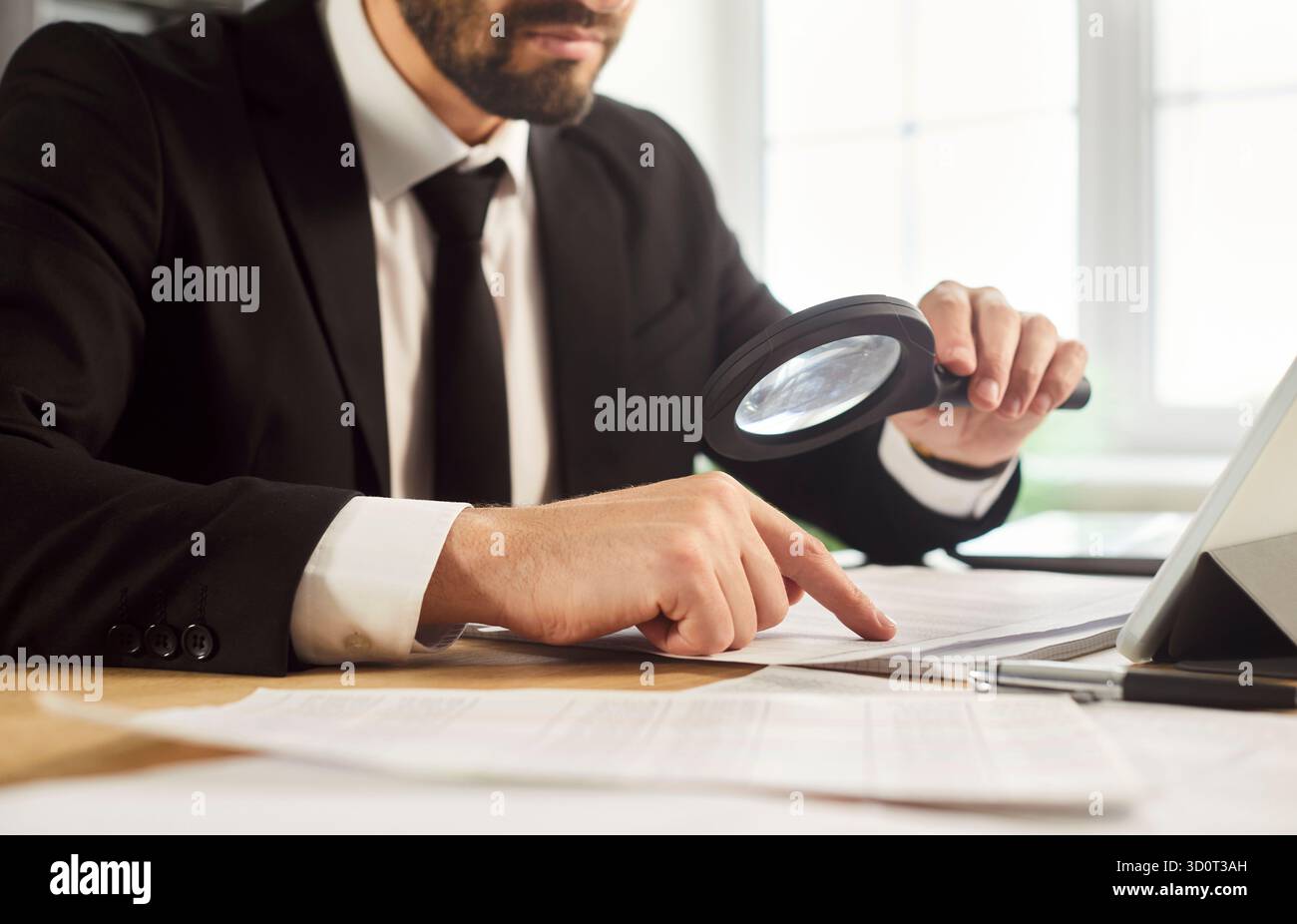Primo piano di un uomo d'affari che controlla i documenti e rivede i dati con una lente di ingrandimento Foto Stock