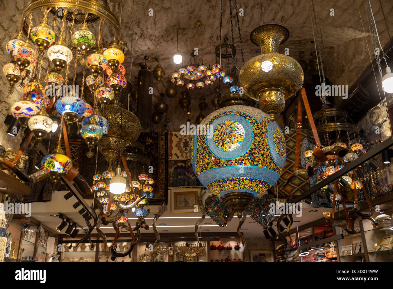 Gerusalemme, Israele, 23 ottobre 2025, numerose lampade e lanterne turche a mosaico dal design vivace e complesso pendono dal soffitto di pietra di una souve Foto Stock