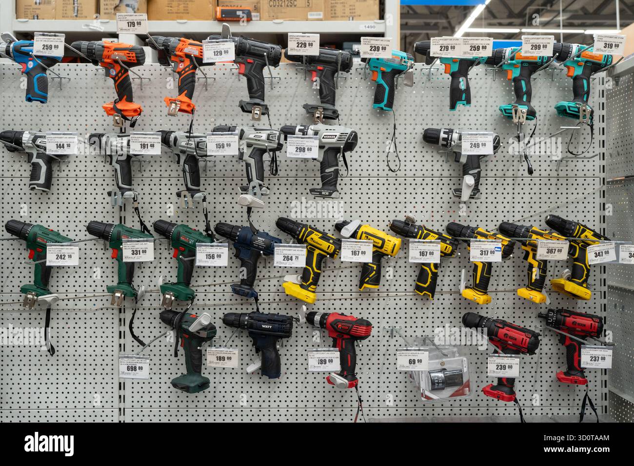 Gamma di trapani elettrici e cacciaviti cordless esposti nel negozio di utensili. Selezione e acquisto di utensili elettrici. Minsk, Bielorussia - 26 giugno 2025 Foto Stock