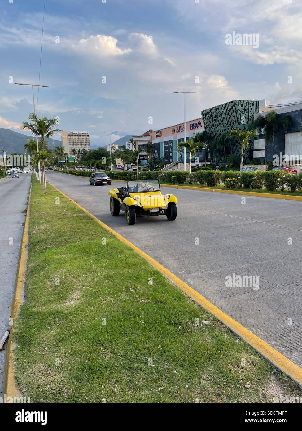 Buggy sulle dune gialle che percorre un ampio viale in una moderna città di montagna, Puerto Vallarta - Immagine stock catturata con smartphone