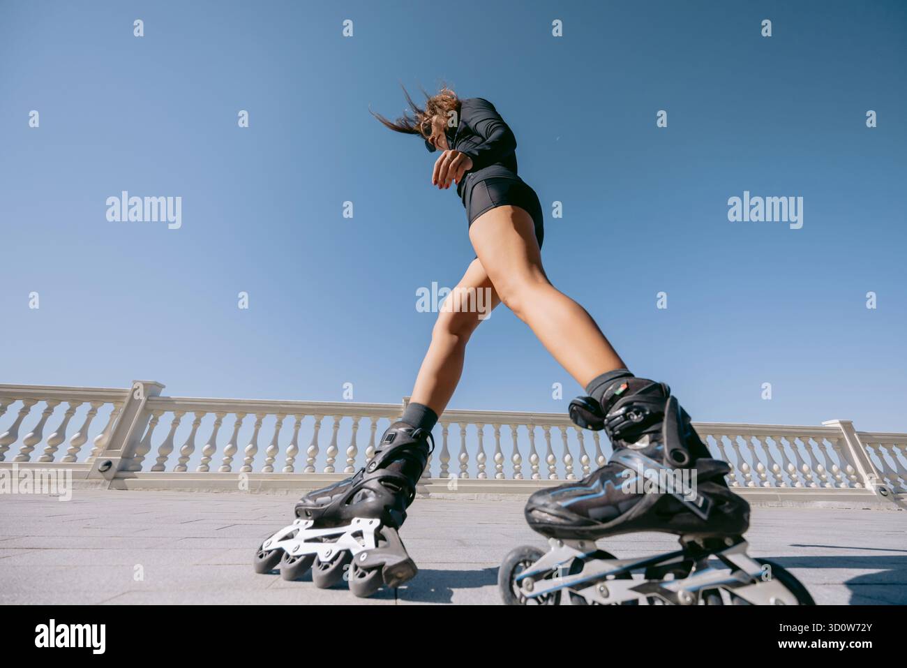Vista ad angolo basso di una donna che corre a pattinaggio nelle giornate di sole Foto Stock
