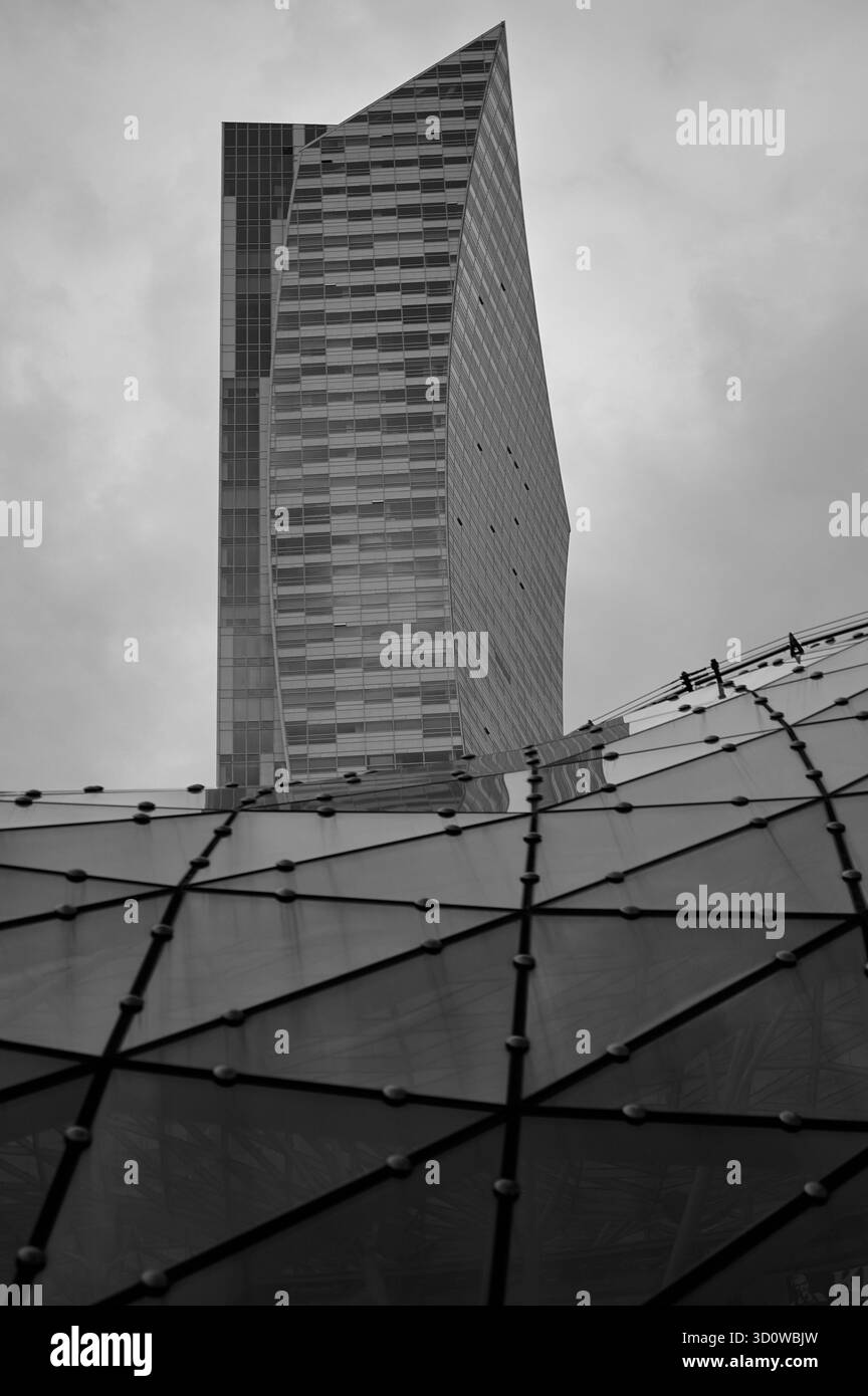 Grattacielo moderno in vetro, prospettiva ad angolo basso, struttura geometrica della facciata, toni di grigio, architettura urbana, cielo coperto, sfondo commerciale, vermi Foto Stock