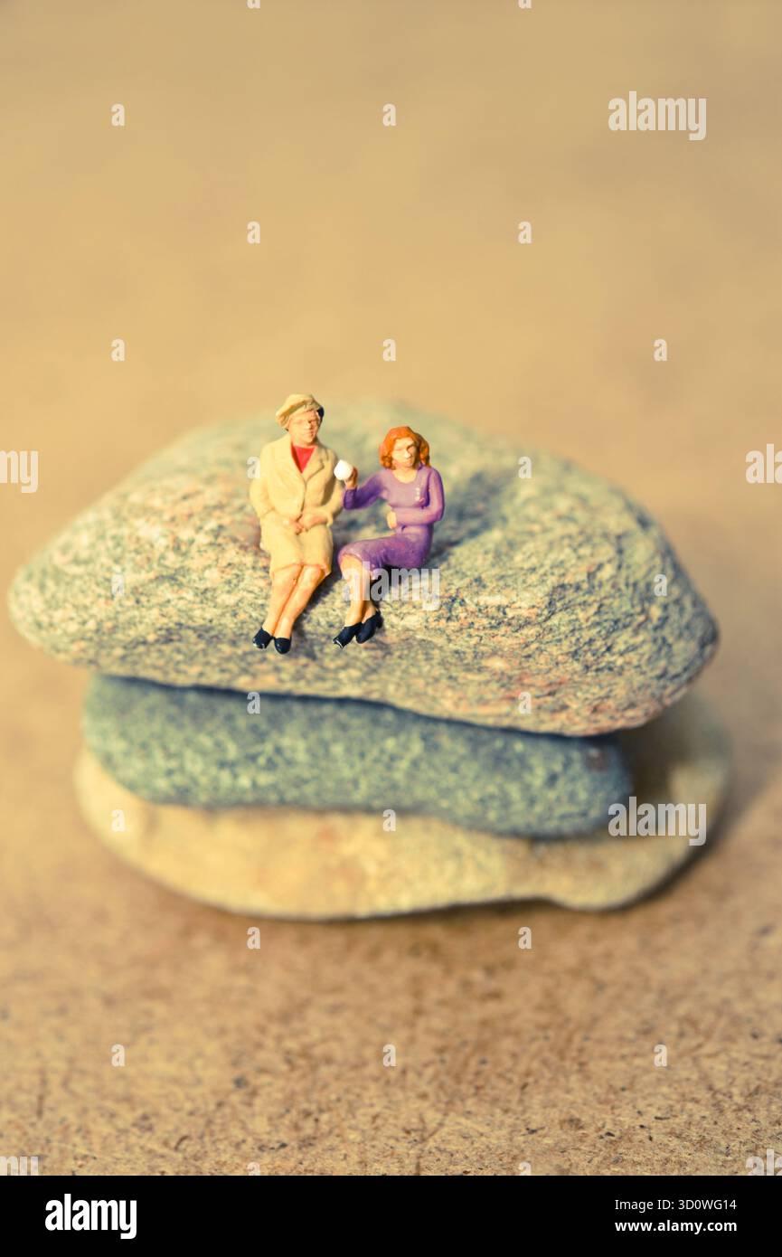 Statuette in miniatura di coppie anziane sedute su pietre impilate, foto concettuale di amore e compagnia Foto Stock