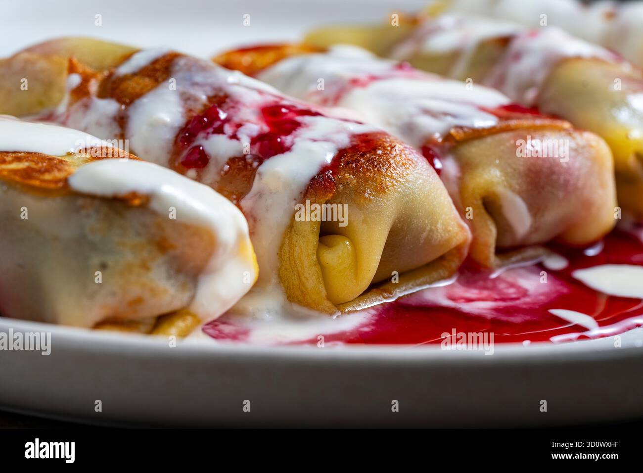 Pancake fritti ripieni di formaggio fresco e ciliegia, dessert dolce sul piatto, primo piano. Cottura fatta in casa. Ottimo fast food a colazione. A. Foto Stock