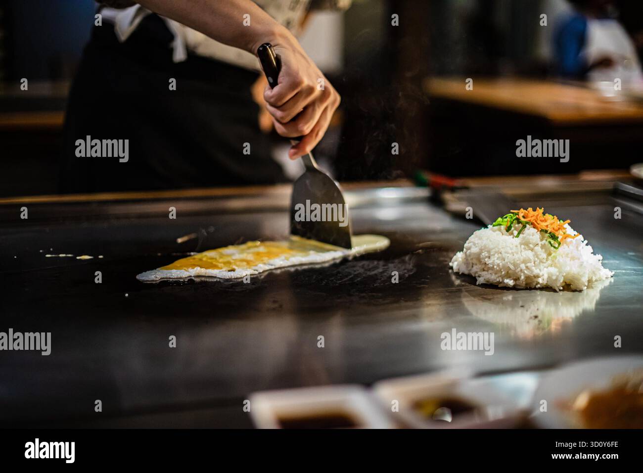 Teppanyaki, spettacolo di teppan di cucina Giapponese presso un ristorante tradizionale. mani di cuoco. Lo chef prepara carne, pesce, riso e verdure su un tavolo caldo davanti agli ospiti. cucine popoli di concetto mondiale Foto Stock