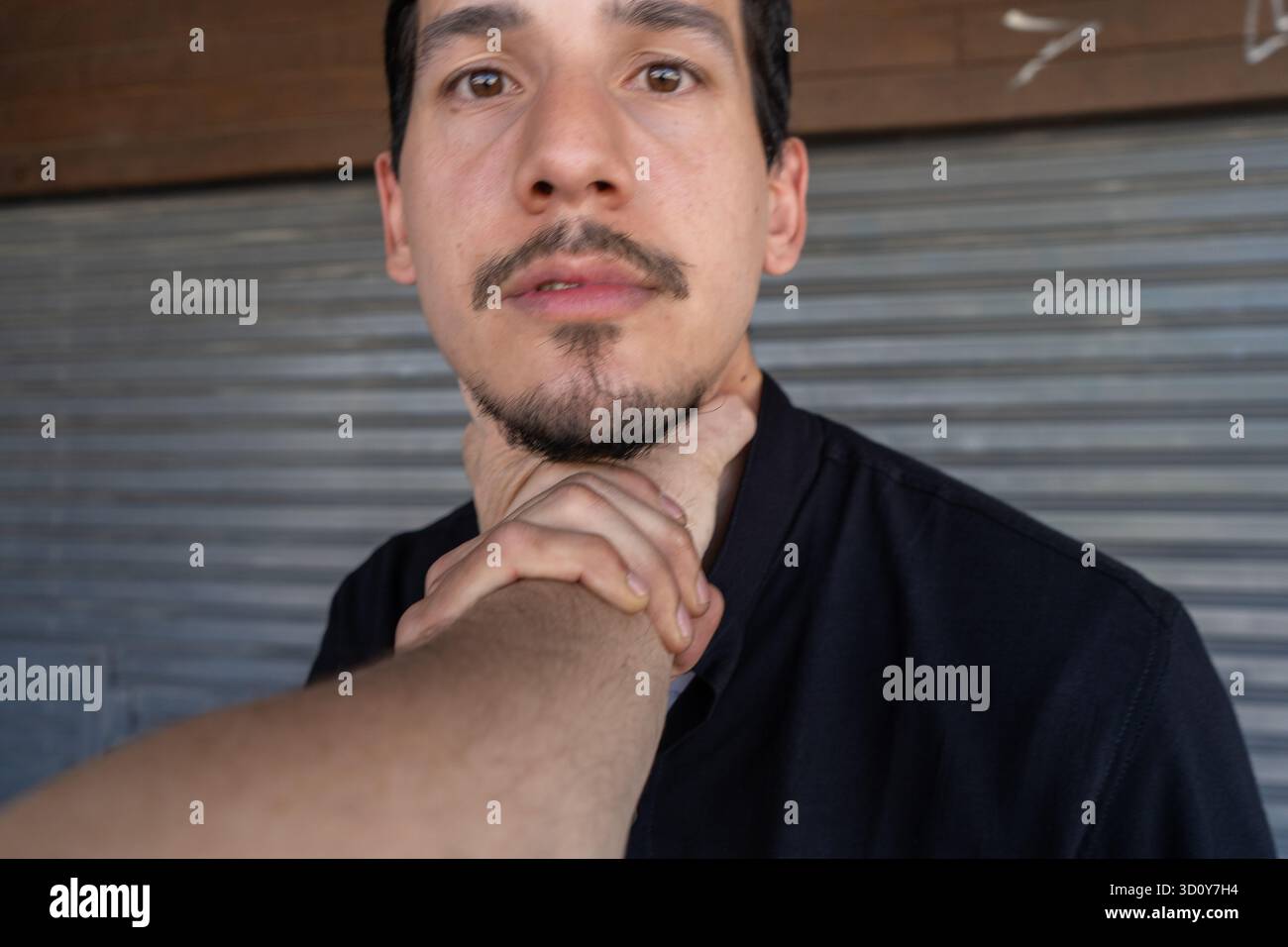 Giovane che riceve una chokehold, vittima di aggressione e violenza in una strada urbana. Pericolo e situazione di conflitto Foto Stock