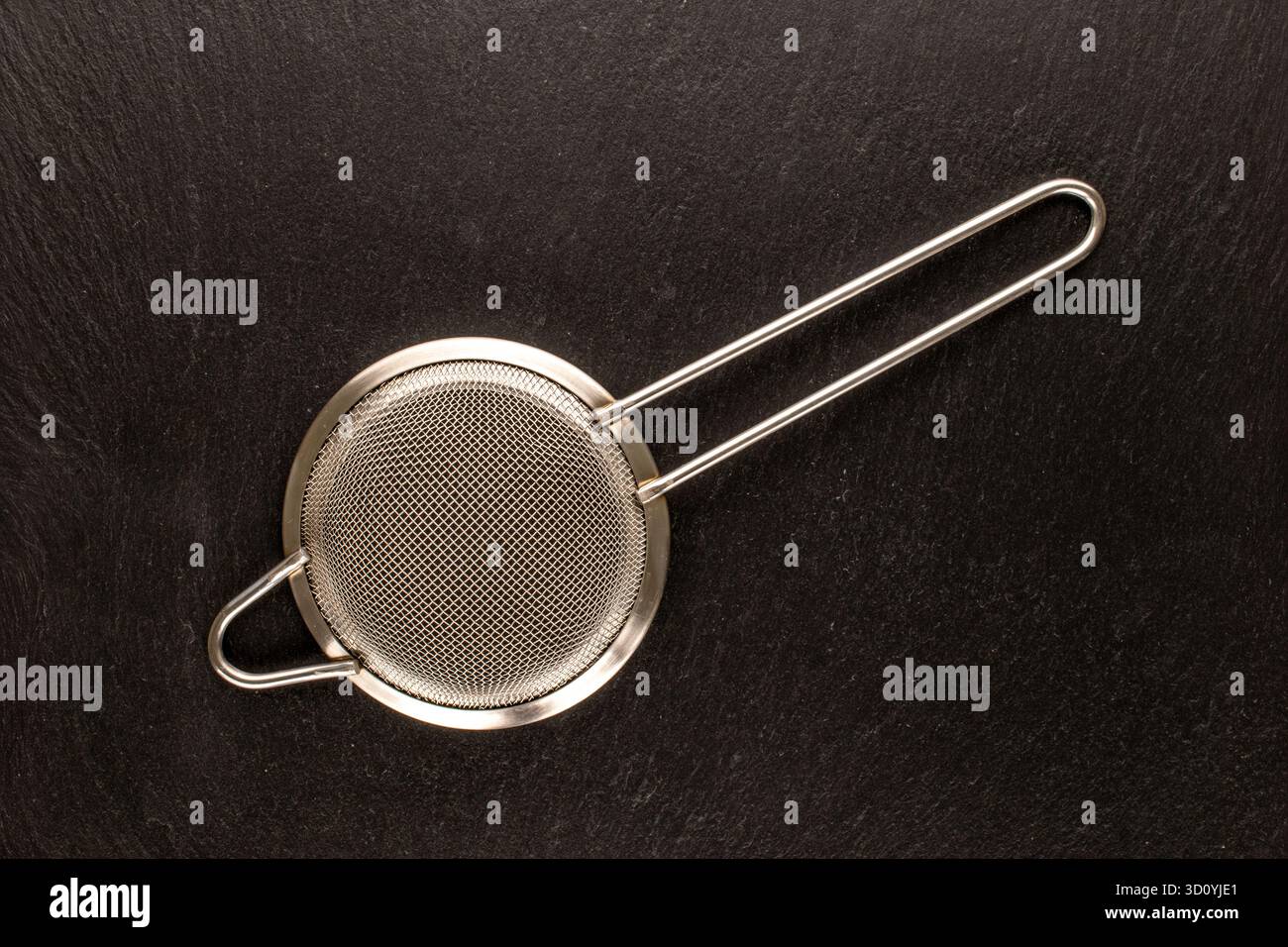 Setaccio da cucina in metallo su ardesia, vista dall'alto. Foto Stock