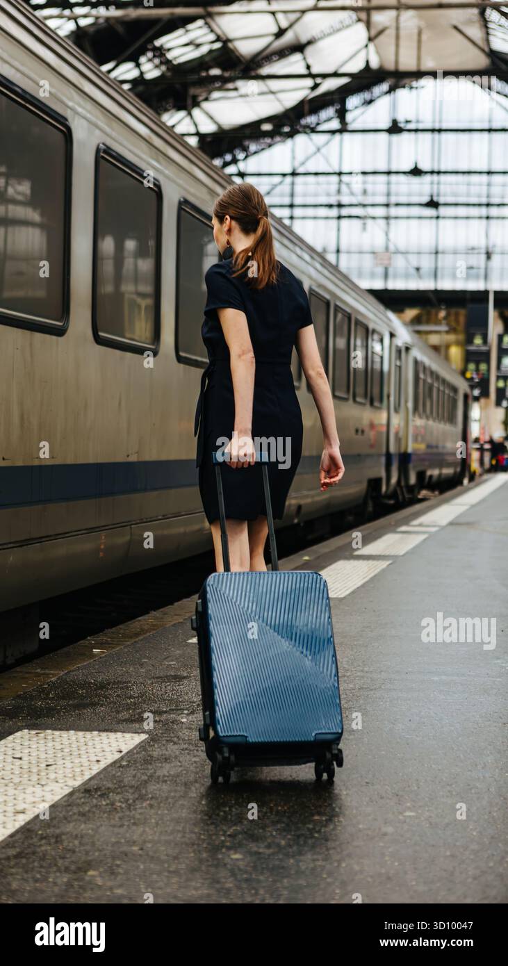 Una donna con bagagli su una piattaforma del treno. Foto Stock