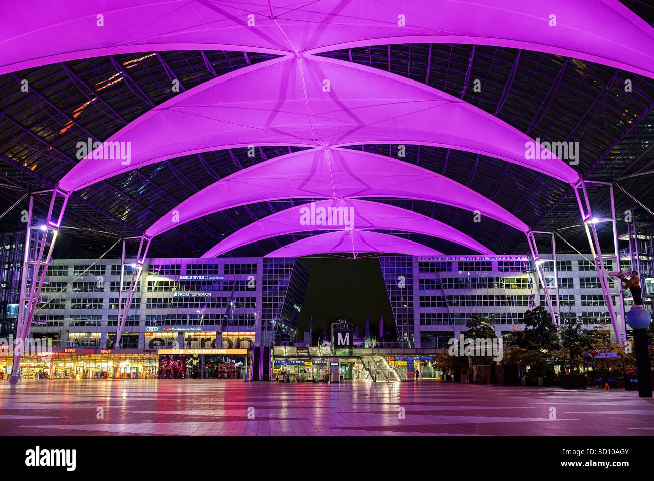 Vista serale del Munich Airport Center Mac Forum presso l'aeroporto di Monaco di Baviera, Germania, una grande area esterna coperta che collega due importanti terminal Foto Stock