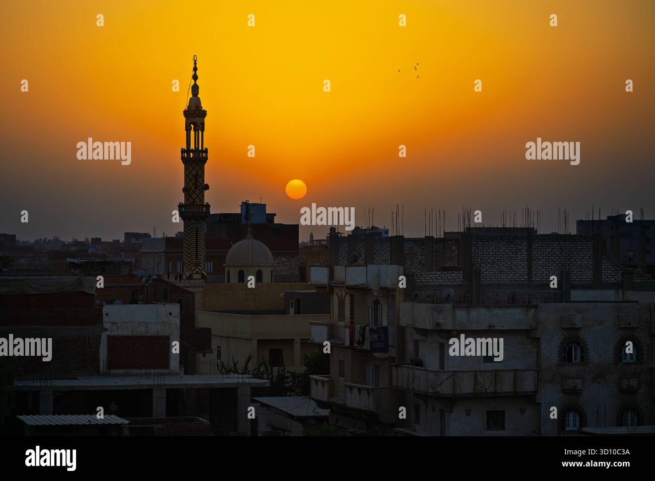 Una moschea e un minareto si stagliano contro un tramonto all'ora d'oro sopra la città del Cairo, in Egitto. Foto Stock
