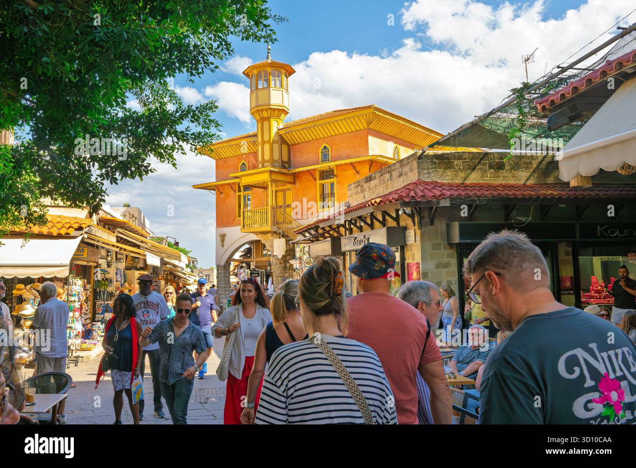 I pedoni camminano attraverso la storica città vecchia medievale con la Moschea Mehmet Aga in lontananza, a Rodi, Grecia. Foto Stock