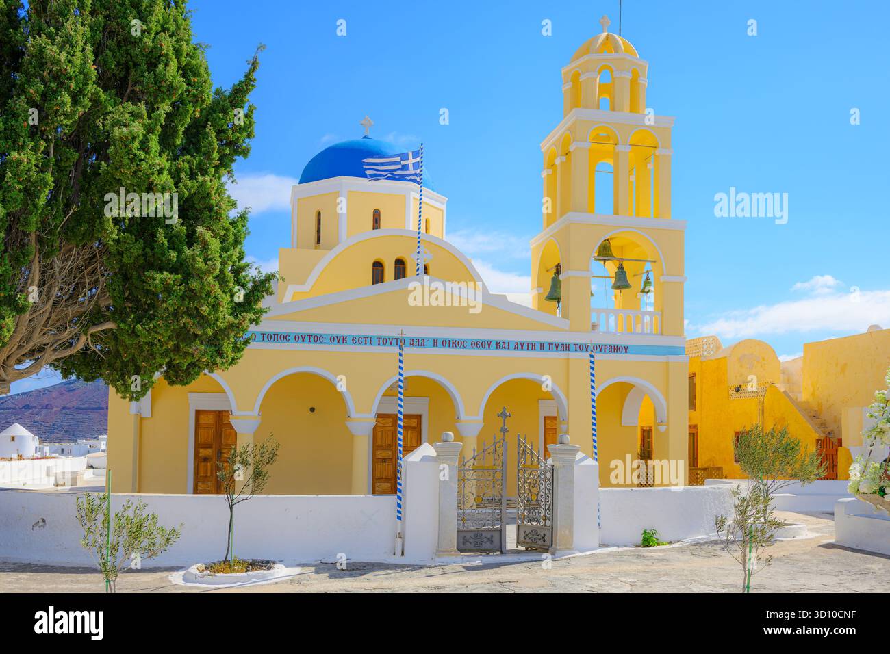 L'esterno giallo brillante, il campanile e la cupola blu della Chiesa di Agios Georgios nel villaggio di Oia, sull'isola di Santorini, in Grecia. Foto Stock