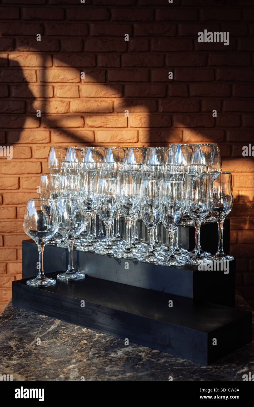 Eleganti oggetti in vetro disposti in file sotto la luce dorata, perfetti per eventi di lusso, marchi da bar o immagini minimaliste per l'ospitalità. Foto Stock