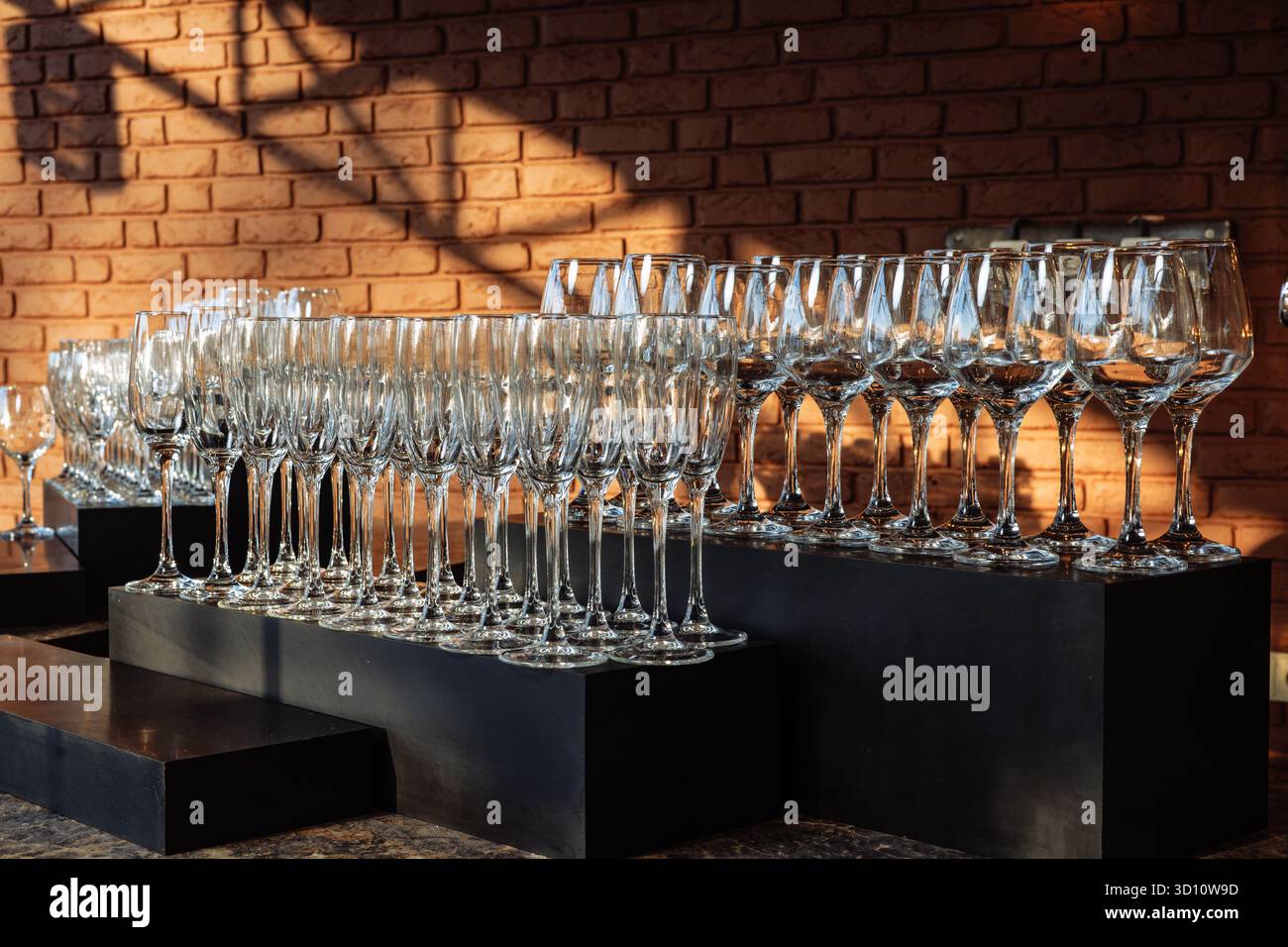 Eleganti oggetti in vetro disposti in file sotto la luce dorata, perfetti per eventi di lusso, marchi da bar o immagini minimaliste per l'ospitalità. Foto Stock